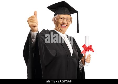 Donna anziana in un abito di laurea in possesso di un diploma e mostrando pollice in alto isolato su sfondo bianco Foto Stock