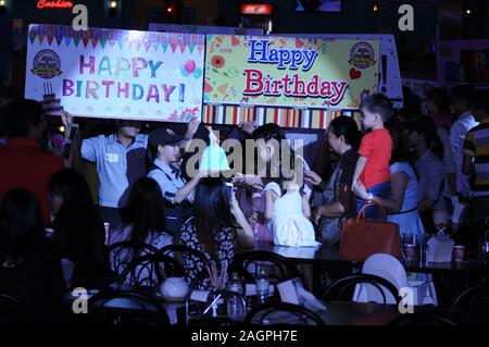 Cambogiano di festa di compleanno, cameriera offre una torta di compleanno e Scintilla & Tawandang Birreria Tedesca, Phnom Penh Cambogia. © Kraig Lieb Foto Stock