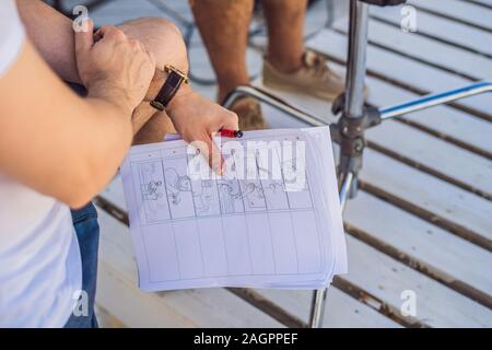 Operatore di ripresa e direttore di parlare del processo di un commerciale riprese video. direttore contiene uno storyboard in mano Foto Stock