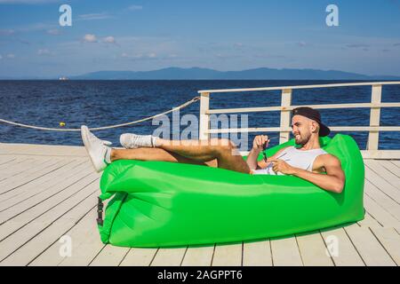 Giovane uomo godendo di piacere, sdraiato sul divano aria Lamzac, vicino al mare Foto Stock