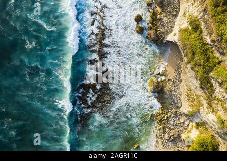 Vista da sopra, splendida vista aerea di una costa rocciosa con una bellissima spiaggia bagnata da un mare agitato durante il tramonto, Nyang Nyang Beach, Bali, Indonesia. Foto Stock