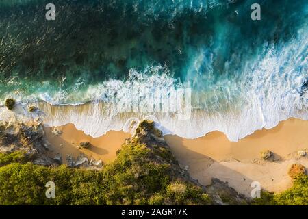 Vista da sopra, splendida vista aerea di una costa rocciosa con una bellissima spiaggia bagnata da un mare agitato durante il tramonto, Nyang Nyang Beach, Bali, Indonesia. Foto Stock