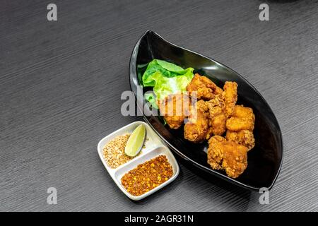 Pezzo di pollo fritto Karaage in nero piatto. Foto Stock