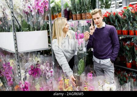 Piuttosto giovane picks orchidee nel negozio. Scelta di fiori in un negozio di fiori Foto Stock