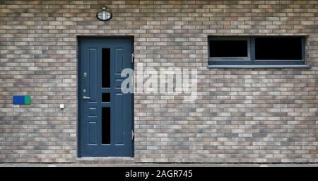 La parete frontale di una produzione di massa standard a basso costo incompiuto edificio residenziale con porta armati isolato Foto Stock