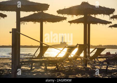 Tramonto sulla spiaggia con ombrelloni e lettini: Il Convento o la spiaggia di San Lorenzo si trova nelle vicinanze di Vieste in Puglia, Italia. Foto Stock