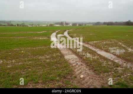 I cingoli del trattore attraverso un campo Dopo forti piogge nelle zone rurali del Bedfordshire England Regno Unito Foto Stock