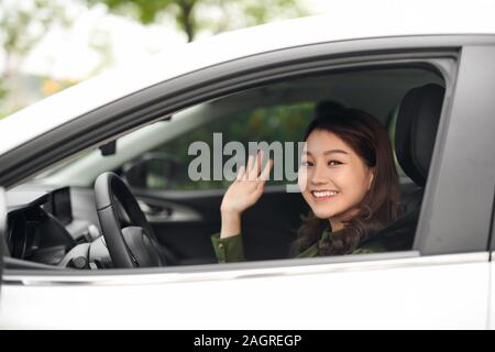 Ciao! Giovane e bella Allegra donna che guarda la fotocamera con il sorriso e sventolare mentre è seduto nella sua auto Foto Stock