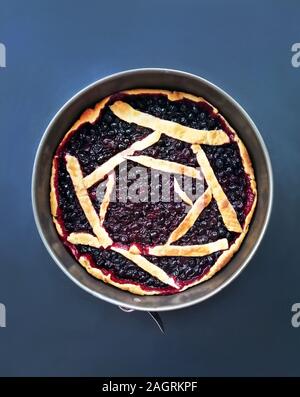 Torta rotonda con nero bacche Ribes su uno sfondo blu, una ricetta di pasta dolce da impasti Foto Stock