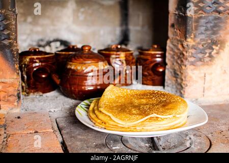 Rosy e frittelle calde cotte in una stufa russa. Maslenitsa - inverno addio. Foto Stock