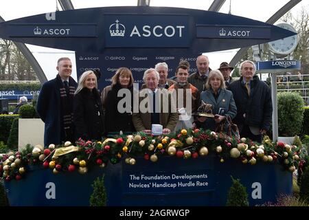 Ascot Racecourse, Berkshire, Regno Unito. Xxi Dec, 2019. Ascot famiglia natale Racing Weekend, Jockey Sean Houlihan vince la Fondazione sviluppi novizi' Handicap corsa ad ostacoli (classe 4) a cavallo che scorre la cadenza. I proprietari e i formatori hanno una foto in parata anello. Proprietaria, la signora C J Dunn, Trainer Bob scudo, Bridgwater, allevatore la signora H R Dunn, Sponsor Super Mare ponteggi. Credito: Alamy Live News/Maureen McLean Credito: Maureen McLean/Alamy Live News Foto Stock