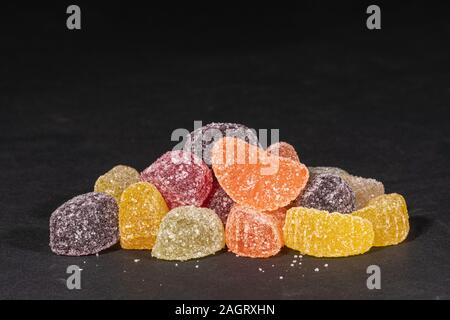 Un mucchio di fruttato gommoso di caramelle gommose su uno sfondo nero con spazio di copia Foto Stock