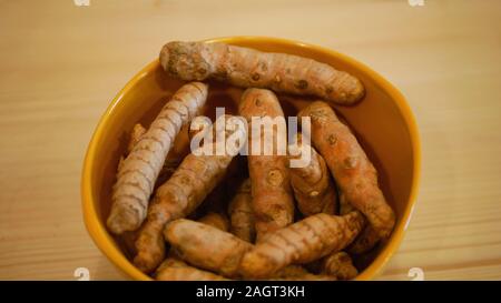 Il rizoma di curcuma radici Curcuma longa nella ciotola, zafferano indiano è cotto vengono essiccati e macinati in una polvere gialla. Utilizzato in curry spezie anti-inflammat Foto Stock