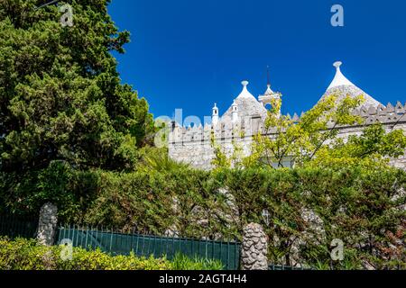 Tetti e recinzione di truli, pitturato di bianco tipico case cilindrico in Alberobello Puglia, Italia con incredibile cielo blu con nuvole, street view Foto Stock
