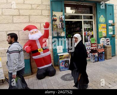 Betlemme, nella Striscia di Gaza. Xxi Dec, 2019. Palestinesi passato a piedi un Babbo Natale a Betlemme, West Bank, Sabato, Dicembre 21, 2019. I turisti si ammassano a Betlemme prima di Natale, per visitare la chiesa della Natività, creduto costruita sopra la stalla dove è nato Gesù. Foto di Debbie Hill/UPI Credito: UPI/Alamy Live News Foto Stock