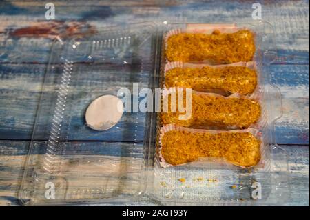 Quattro torte in un contenitore di plastica su un sfondo di legno Foto Stock