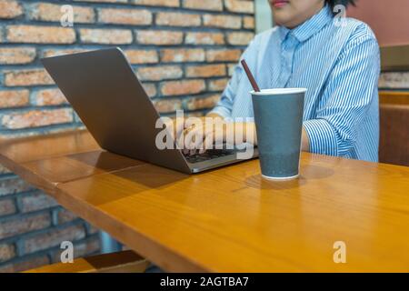 Giovane donna asiatica utilizzando laptop a tavola in coffee shop Foto Stock