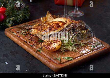 Grigliata di pesce dorado farciti con diversi ortaggi. Decorazioni di Natale l'impostazione. Foto Stock