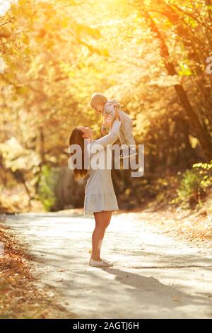 Madre bella gioca con suo figlio in natura. autumn landscape. Tramonto. Silhouette di una giovane madre e il suo piccolo figlio al tramonto Foto Stock