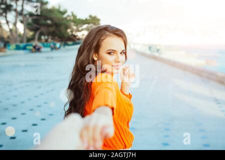 Seguimi - felice giovane donna tirando ragazzo mano - Mano nella mano a camminare su una luminosa giornata di sole - Concetto di spensierata vita moderna. Foto Stock