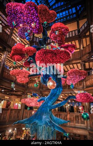 Central London, Londra, 21 dic 2019. "L'albero della libertà", una bella floating albero di Natale in atrio al Liberty's, un gigante blu e fucsia albero di bonsai coperto nel decor. Negozi, alberghi, ristoranti e residenze hanno tutte addobbate le sale decorate e i loro ingressi nella festosa splendore intorno a Mayfair e Oxford Street e Regent Street a Londra negli ultimi giorni prima di Natale. Foto Stock