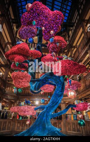 Central London, Londra, 21 dic 2019. "L'albero della libertà", una bella floating albero di Natale in atrio al Liberty's, un gigante blu e fucsia albero di bonsai coperto nel decor. Negozi, alberghi, ristoranti e residenze hanno tutte addobbate le sale decorate e i loro ingressi nella festosa splendore intorno a Mayfair e Oxford Street e Regent Street a Londra negli ultimi giorni prima di Natale. Foto Stock