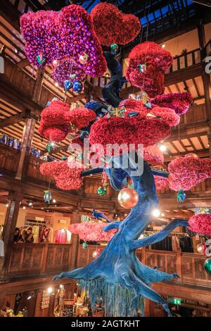 Central London, Londra, 21 dic 2019. "L'albero della libertà", una bella floating albero di Natale in atrio al Liberty's, un gigante blu e fucsia albero di bonsai coperto nel decor. Negozi, alberghi, ristoranti e residenze hanno tutte addobbate le sale decorate e i loro ingressi nella festosa splendore intorno a Mayfair e Oxford Street e Regent Street a Londra negli ultimi giorni prima di Natale. Foto Stock