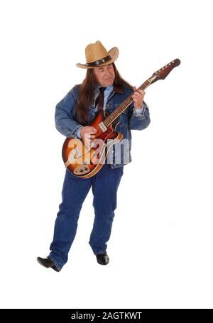 Un bel uomo indigeni in un paio di jeans giacca, pantaloni e un cappello da cowboy standing e suonare la chitarra, isolato per sfondo bianco Foto Stock