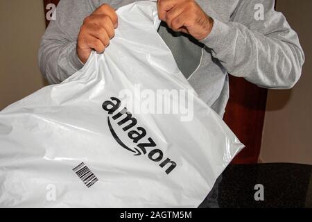 Dubai - EMIRATI ARABI UNITI - 20 dicembre 2019: l uomo è in plastica apertura di consegna pacchi di Amazon. Amazon consegna confezione di plastica. Foto Stock