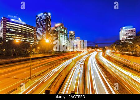 Ampia multi lane Warringah freeway all'ingresso del Sydney Harbour Tunnel e ponte al tramonto nella parte anteriore del grattacielo di torri di uffici in Nord SYdne Foto Stock