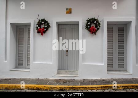 Questi porta e 2 finestre sono parte di una casa signorile edificio dipinto di bianco nella storica vecchia San Juan. Le pareti bianche sono decorate con 2 corone. Foto Stock