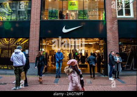 Gli amanti dello shopping a piedi passato il nike store.Questa giornata segna la fine della stagione di shopping che ha avuto inizio il venerdì nero. In Amsterdam, migliaia di turisti e persone hanno preso le principali vie dello shopping nella capitale olandese a fare gli ultimi acquisti e visite turistiche. Foto Stock