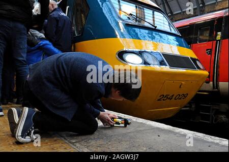 Stazione di King Cross, Londra, Regno Unito. Il 21 dicembre 2019. Londra nord-orientale della società ferroviaria restaurato un InterCity 125 insieme al suo originale British Rail livrea per una speciale della durata di quattro giorni in giro per la rete LNER come i treni fine 40 anni di servizio sulla East Coast Main Line. Un appassionato di giovani fotografie del suo modello HST di fronte la cosa reale. G.P. Essex/Alamy Live News Foto Stock