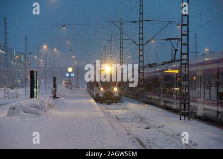 Helsinki, Finlandia - 6 Febbraio 2019: un locale dei pendolari treno in arrivo a Helsinki la stazione ferroviaria centrale in pesante tempesta di neve appena prima dell'alba in Foto Stock