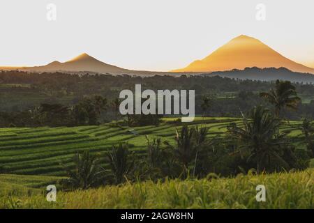 Incredibile caldo arancio tramonto sul famoso Jatiluwih terrazzi di riso e Gunung Agung volcano view. Meta turistica molto landmark in Bali. Benvenuto a Bali il concetto di viaggio. Foto Stock
