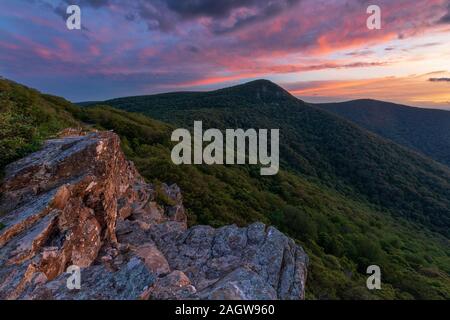 Bel colore arancione, giallo, viola, blu tramonto con le rocce in primo piano e le montagne in distanza nel Parco Nazionale di Shenandoah Foto Stock