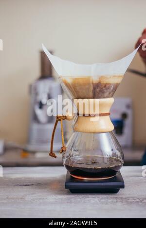 Brewign terza onda caffè con vetro chemex e bollitore antigoccia per puro gusto nel buon design sul tavolo di legno Foto Stock