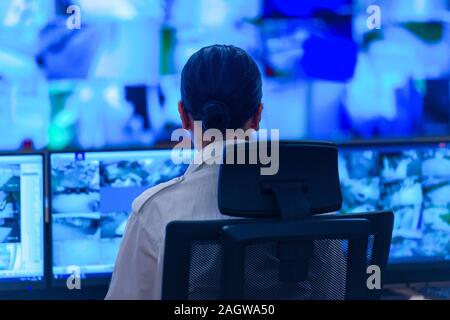 Nel sistema di controllo, camera operatore tecnico lavora presso la propria workstation con monitor multipli, guardia di sicurezza lavorando su più monitor. Foto Stock