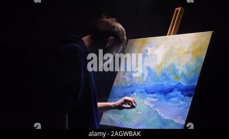 Artista copista paint seascape con nave in oceano. Fumo Vaper vape e-sigaretta. Artigiano arredatore disegnare come barca vela sul mare blu con colori acrilici. Foto Stock