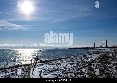 Uomo che cammina in spiaggia in una fredda giornata invernale Foto Stock