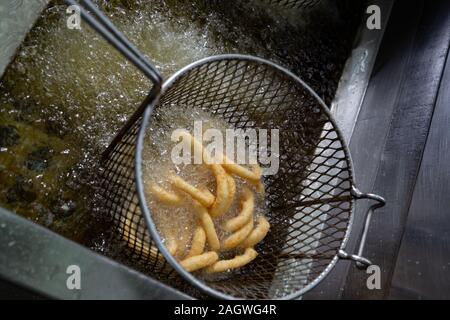 Anelli di cipolla in una friggitrice con olio bollente Foto Stock