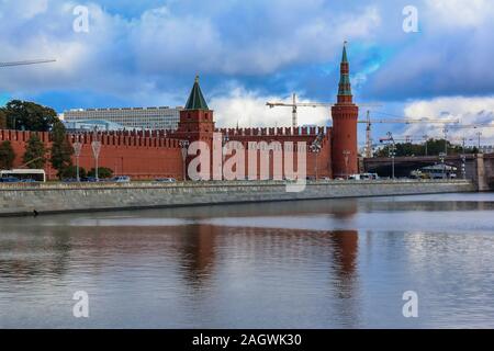 Vista diurna del Cremlino rosso parete e torre con il traffico sul terrapieno Kremlevskaya dal fiume Moskva con un cielo nuvoloso a Mosca, Russia Foto Stock