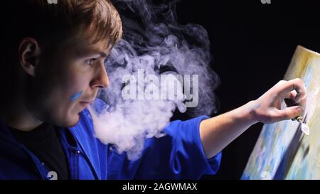 Artista copista paint seascape con nave in oceano. Fumo Vaper vape e-sigaretta. Artigiano arredatore disegnare come barca vela sul mare blu con colori acrilici. Foto Stock