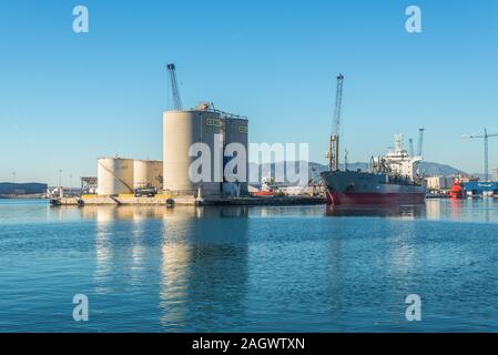 Malaga, Spagna - 4 Dicembre 2018: Cemento nave da trasporto Gloria Tellus e lo stoccaggio in bulk di calcestruzzo Cemento silos e serbatoi di Bacardi all ingresso di Malaga Foto Stock