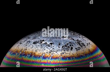 Iridato emisferica superficie di una bolla di sapone su uno sfondo nero isolato. La fotografia macro Foto Stock