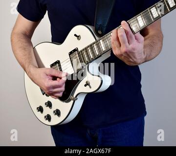 L'uomo gioca un bianco con la chitarra elettrica con pickup humbucker. Foto Stock
