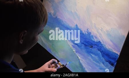Artista copista paint seascape con nave in oceano. Artigiano arredatore disegnare come barca vela sul mare blu con olio acrilico colore. Disegnare la spazzola, coltello tavolozza. Foto Stock