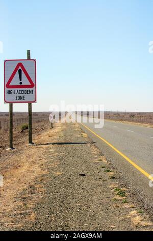 Lungo e quasi vuoto road nel Karoo area desertica in Sud Africa con 'Incidente di alta zona' firmare Foto Stock