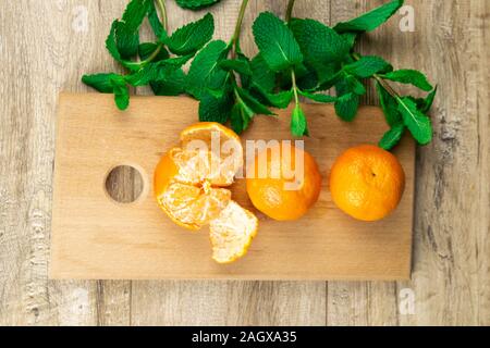 Tre i tangerini su una tavola di legno Foto Stock