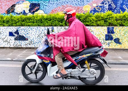 Il vietnamita uomo che indossa red cape sul motociclo, Hanoi Vietnam Foto Stock